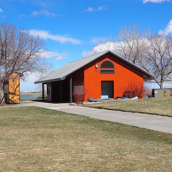 Red pole barn by a lake and grass area